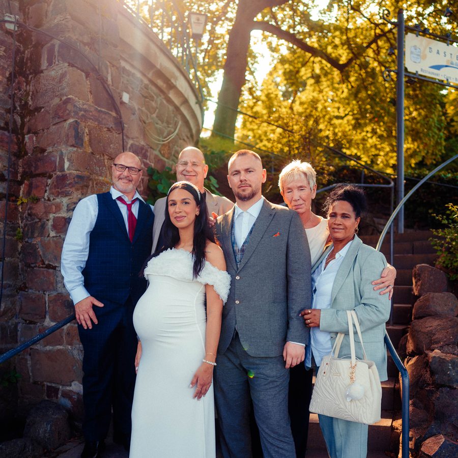 Brautpaar mit der Familie auf einer Treppe im Gegenlicht